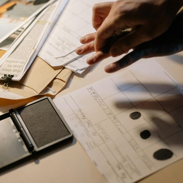 Detailed view of fingerprinting process with documents and ink pad on a desk, focusing on identity verification.